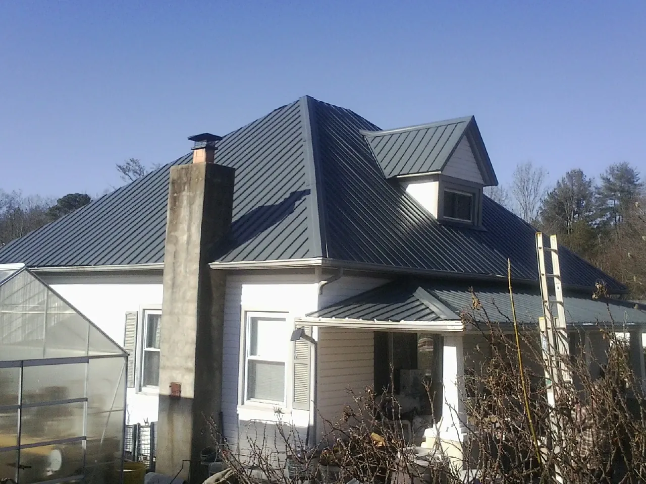 Dark blue standing seam metal roof on a white farmhouse with dormer — Slate & Tile Roof Repair by Roofing Brothers in Bryn Mawr