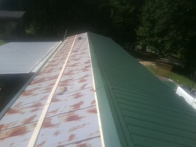 Old rusted panels beside newly installed green metal roofing — Wind Damage Roof Repair by Roofing Brothers in Bryn Mawr