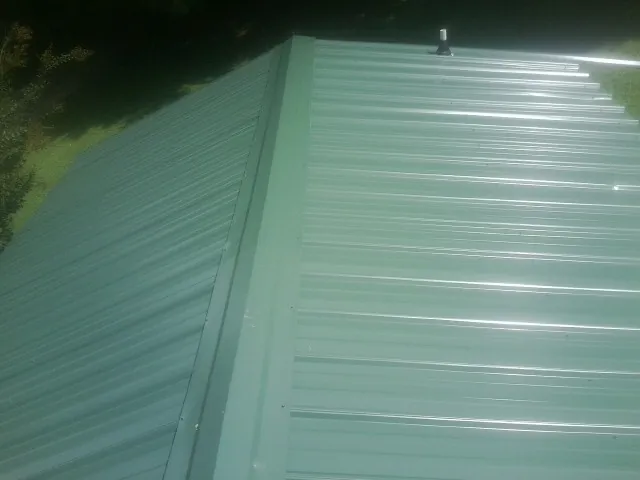 New green metal panels meeting at the ridge of a roof — Flat Roof Repair work by our crew in Bryn Mawr
