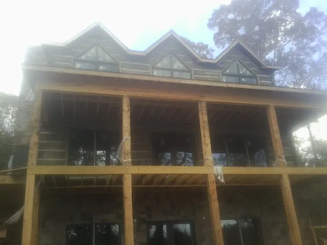 Dormers and porch framing on a large log home under construction — Roof Coating work by our crew in Bryn Mawr