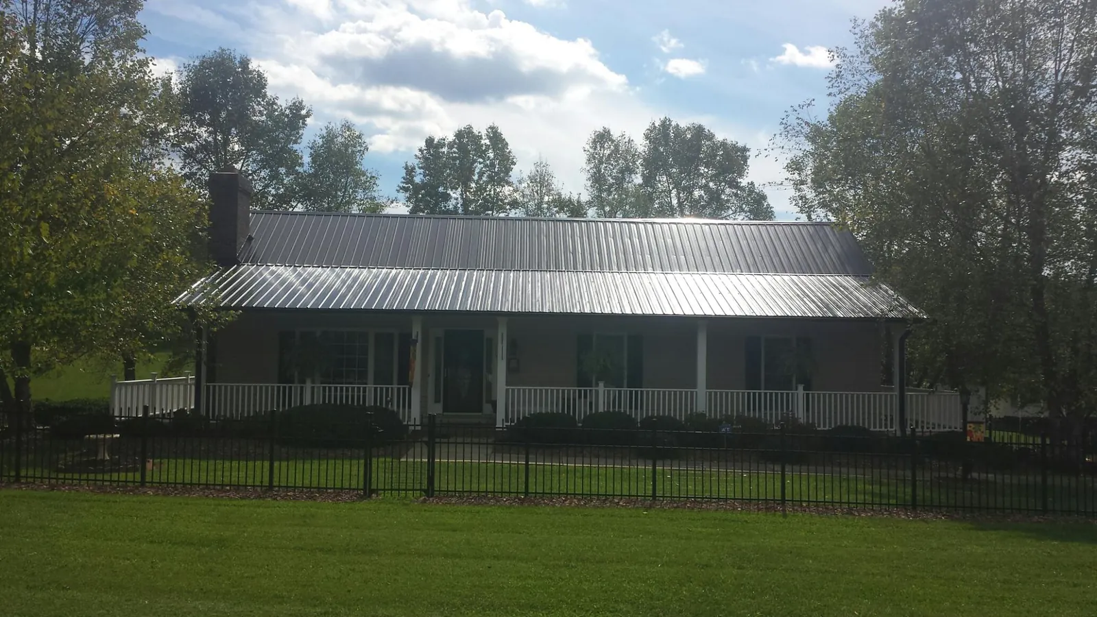 Gray metal roof on a brick ranch with a full width front porch — Gutter Guard Installation work by our crew in Bryn Mawr