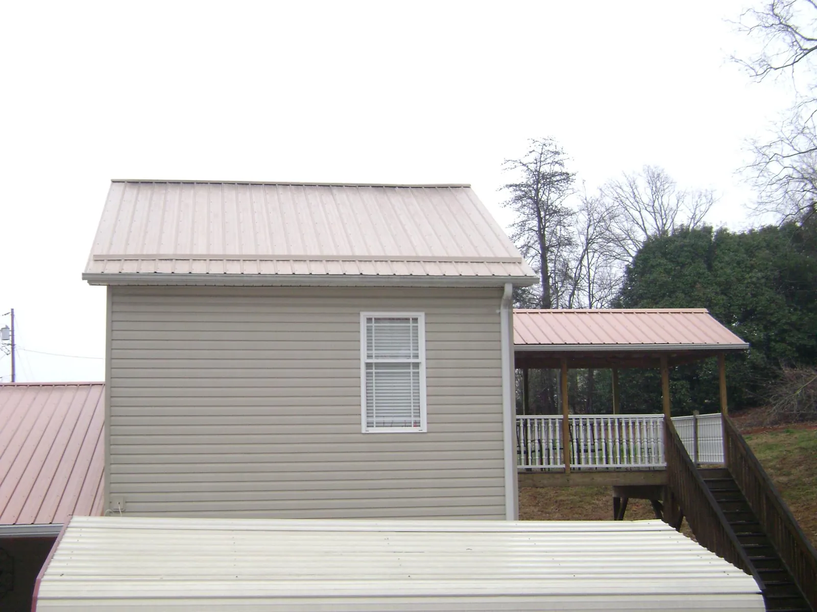 Tan metal roofs on a two story addition and attached porch, from a Roof Replacement job in Bryn Mawr