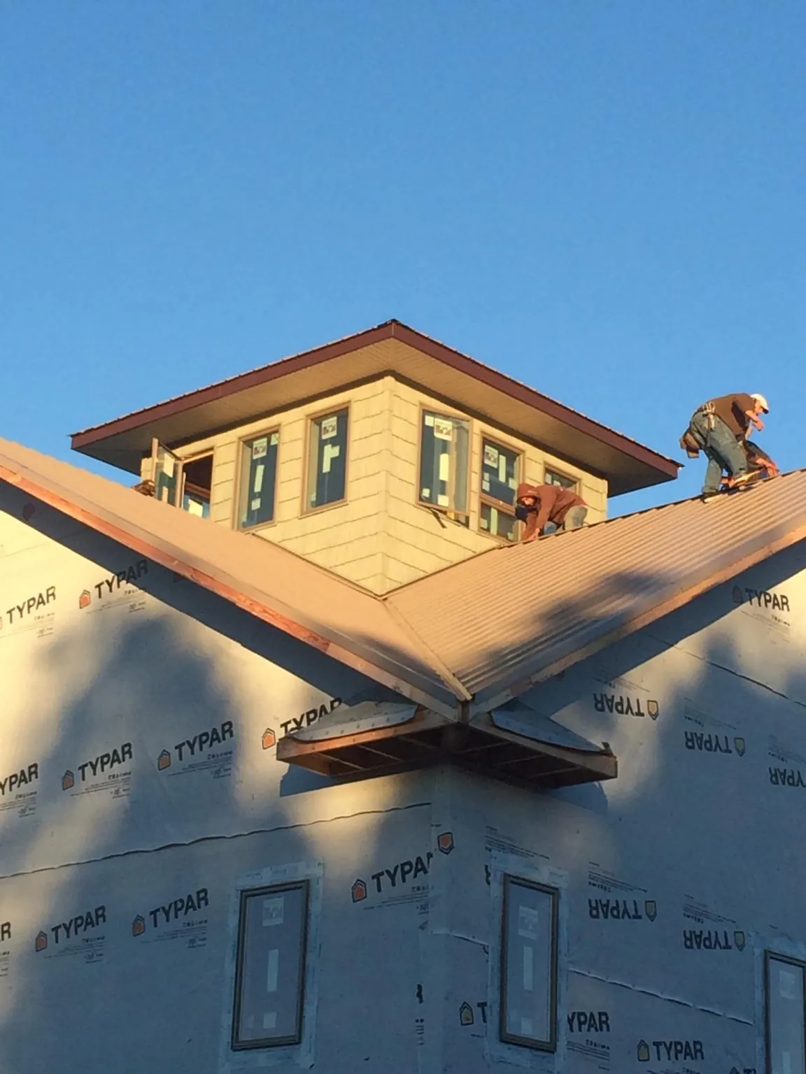 Roofers working around a rooftop cupola on a new metal roof at sunset — Roof Waterproofing in Bryn Mawr by Roofing Brothers
